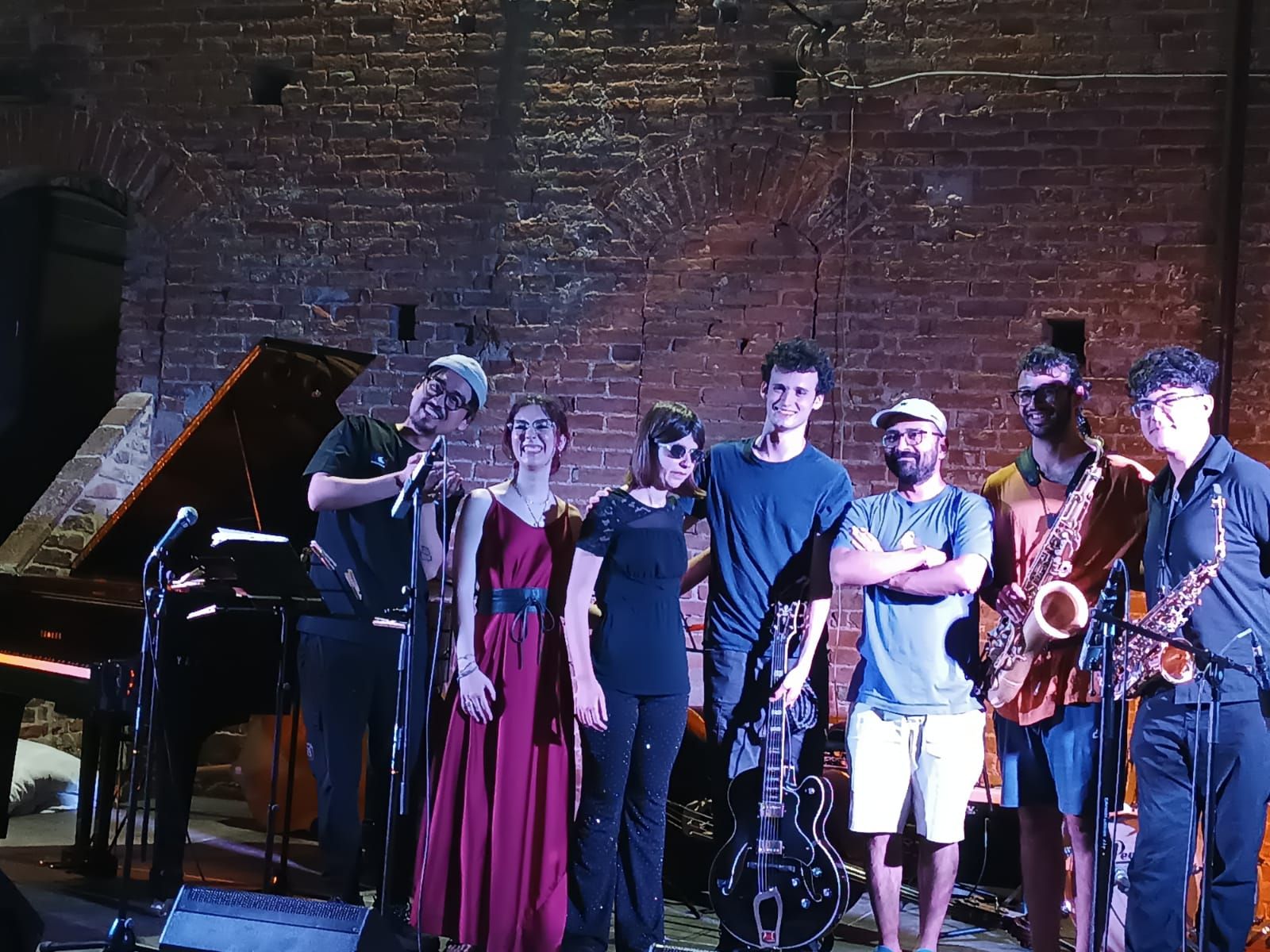 Anna con il gruppo sul palco, davanti a un muro di mattoni, dopo il concerto