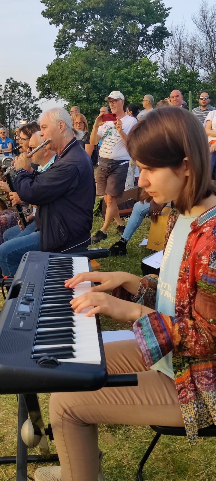 Anna alla tastiera in un concerto all'aperto sul prato, con fiati e pubblico