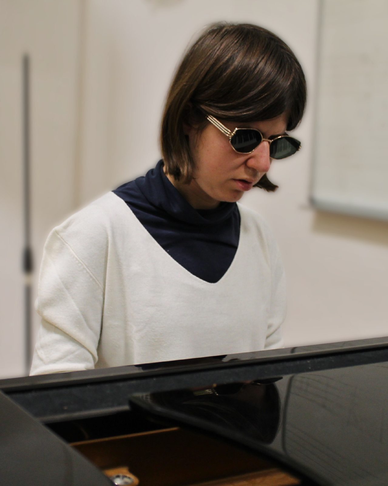 Anna al pianoforte, con occhiali scuri e maglione bianco