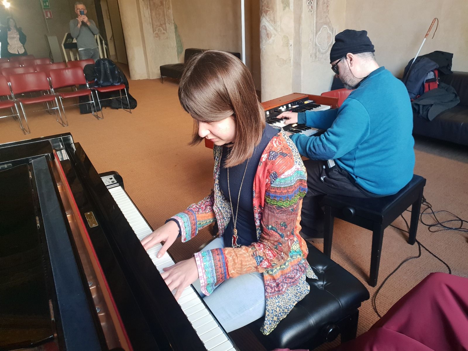 Anna suona il pianoforte, un musicista accanto